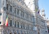 A detailed view of the Gothic-style Town Hall in Brussels with flags and intricate stonework.