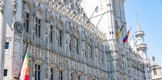 A detailed view of the Gothic-style Town Hall in Brussels with flags and intricate stonework.