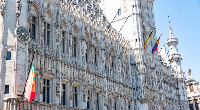 Jersey City Mayor James Solomon Joins Global Leadership Program A detailed view of the Gothic-style Town Hall in Brussels with flags and intricate stonework.