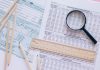 A high angle view showing IRS tax forms with pencils, ruler, and magnifying glass for financial planning.