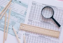 A high angle view showing IRS tax forms with pencils, ruler, and magnifying glass for financial planning.