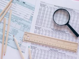 A high angle view showing IRS tax forms with pencils, ruler, and magnifying glass for financial planning.