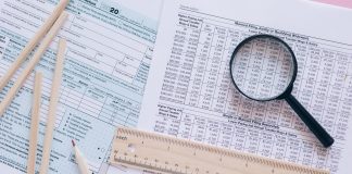 A high angle view showing IRS tax forms with pencils, ruler, and magnifying glass for financial planning.