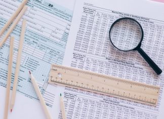 A high angle view showing IRS tax forms with pencils, ruler, and magnifying glass for financial planning.