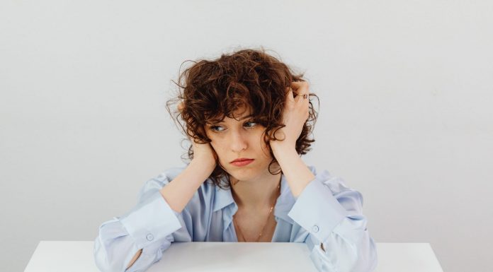 A woman in a blue blouse looks worried with a dollar bill on a table, symbolizing financial stress.