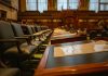 A detailed view of an empty legislative chamber with rows of desks and microphones, evoking governance.