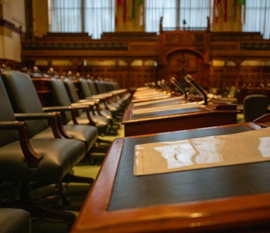 A detailed view of an empty legislative chamber with rows of desks and microphones, evoking governance.