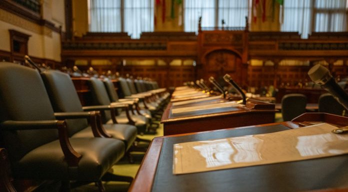 A detailed view of an empty legislative chamber with rows of desks and microphones, evoking governance.
