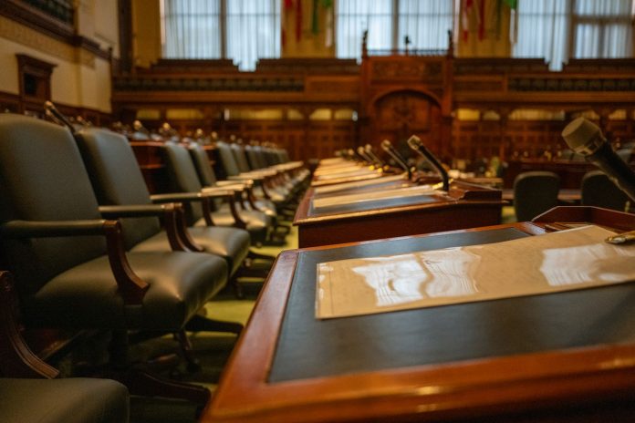 jersey-city-s-new-council-member-calls-for-public- A detailed view of an empty legislative chamber with rows of desks and microphones, evoking governance.