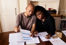 Jersey City’s Triple Tax Hikes Strain Families and Businesses A couple sitting at a table reviewing financial documents, highlighting domestic budgeting.