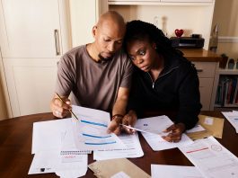 Jersey City’s Triple Tax Hikes Strain Families and Businesses A couple sitting at a table reviewing financial documents, highlighting domestic budgeting.