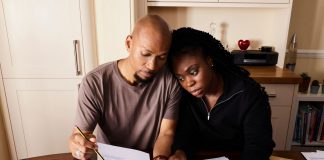 A couple sitting at a table reviewing financial documents, highlighting domestic budgeting.