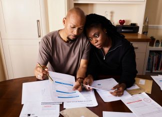 Jersey City’s Triple Tax Hikes Strain Families and Businesses A couple sitting at a table reviewing financial documents, highlighting domestic budgeting.