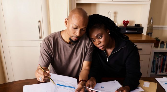 A couple sitting at a table reviewing financial documents, highlighting domestic budgeting.