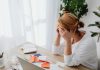 Woman stressed over financial receipts at a desk, dealing with expenses and calculations.