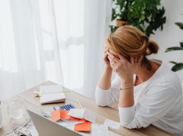 Jersey City Tax Hike: Homeowners Demand Answers, Not Excuses Woman stressed over financial receipts at a desk, dealing with expenses and calculations.