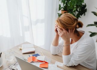 Woman stressed over financial receipts at a desk, dealing with expenses and calculations.