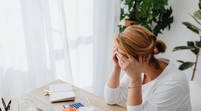 Jersey City Tax Hike: Homeowners Demand Answers, Not Excuses Woman stressed over financial receipts at a desk, dealing with expenses and calculations.