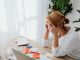 Woman stressed over financial receipts at a desk, dealing with expenses and calculations.