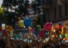 A lively crowd captures a festive street scene filled with colorful balloons and vibrant energy.