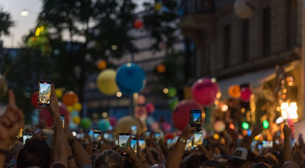 A lively crowd captures a festive street scene filled with colorful balloons and vibrant energy.