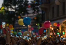 A lively crowd captures a festive street scene filled with colorful balloons and vibrant energy.