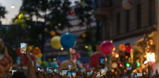A lively crowd captures a festive street scene filled with colorful balloons and vibrant energy.