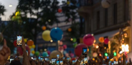 A lively crowd captures a festive street scene filled with colorful balloons and vibrant energy.