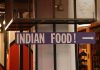 Indoor setting with a large sign reading 'Indian Food' pointing directionally.