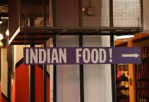 Indoor setting with a large sign reading 'Indian Food' pointing directionally.