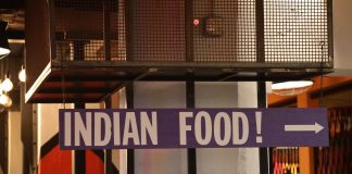 Indoor setting with a large sign reading 'Indian Food' pointing directionally.