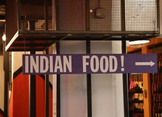 Indoor setting with a large sign reading 'Indian Food' pointing directionally.