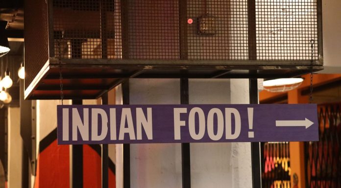 Indoor setting with a large sign reading 'Indian Food' pointing directionally.