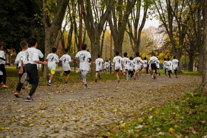 A group of kids participating in a running event in a leafy park in Bursa, Türkiye.