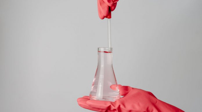Lead in Water: How One Question Built a Newark Movement Laboratory scene showing red-gloved hands holding a flask with clear liquid.