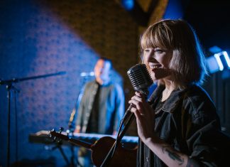 Live Music in August: Pet Shop’s Tenth Birthday, Summerfest, More Smiling caucasian woman singing with vintage microphone during live music performance.