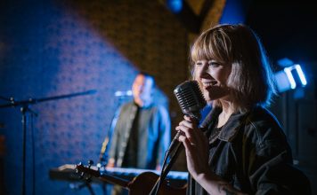Live Music in August: Pet Shop’s Tenth Birthday, Summerfest, More Smiling caucasian woman singing with vintage microphone during live music performance.