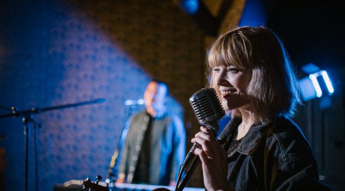Live Music in August: Pet Shop’s Tenth Birthday, Summerfest, More Smiling caucasian woman singing with vintage microphone during live music performance.