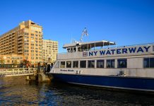 NY Waterway ferry docking at Hoboken, NJ against a clear blue sky, showcasing urban architecture.