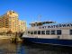 NY Waterway ferry docking at Hoboken, NJ against a clear blue sky, showcasing urban architecture.