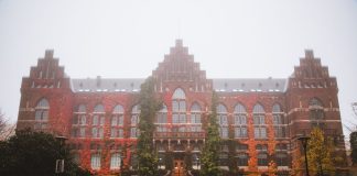Historic Lund University Library facade with autumn foliage and fog, Sweden.