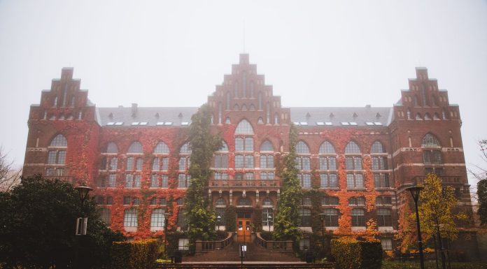 Historic Lund University Library facade with autumn foliage and fog, Sweden.