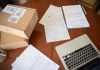 Flat lay of a workspace with laptop, documents, and cardboard boxes for e-commerce operations.