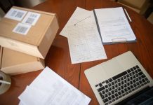 Flat lay of a workspace with laptop, documents, and cardboard boxes for e-commerce operations.