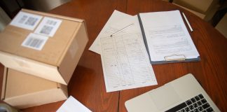 Flat lay of a workspace with laptop, documents, and cardboard boxes for e-commerce operations.