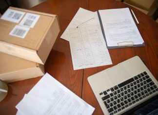 Flat lay of a workspace with laptop, documents, and cardboard boxes for e-commerce operations.