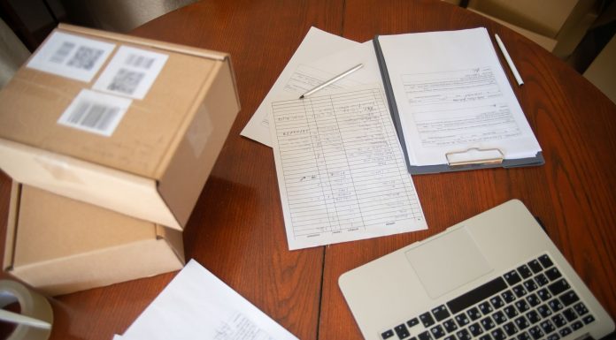Flat lay of a workspace with laptop, documents, and cardboard boxes for e-commerce operations.