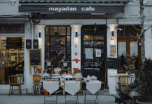 An inviting outdoor café showcasing local food, menu boards, and charming decorations in a quaint neighborhood setting.
