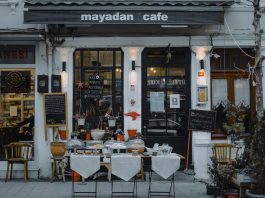 An inviting outdoor café showcasing local food, menu boards, and charming decorations in a quaint neighborhood setting.