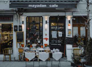 An inviting outdoor café showcasing local food, menu boards, and charming decorations in a quaint neighborhood setting.